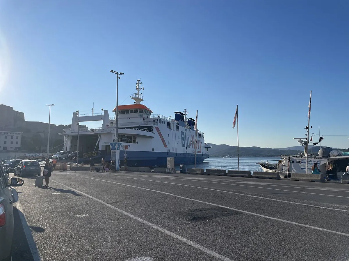 Auto che sbarcano da un traghetto Blu Navy, con la corsia d’imbarco vuota sulla banchina davanti