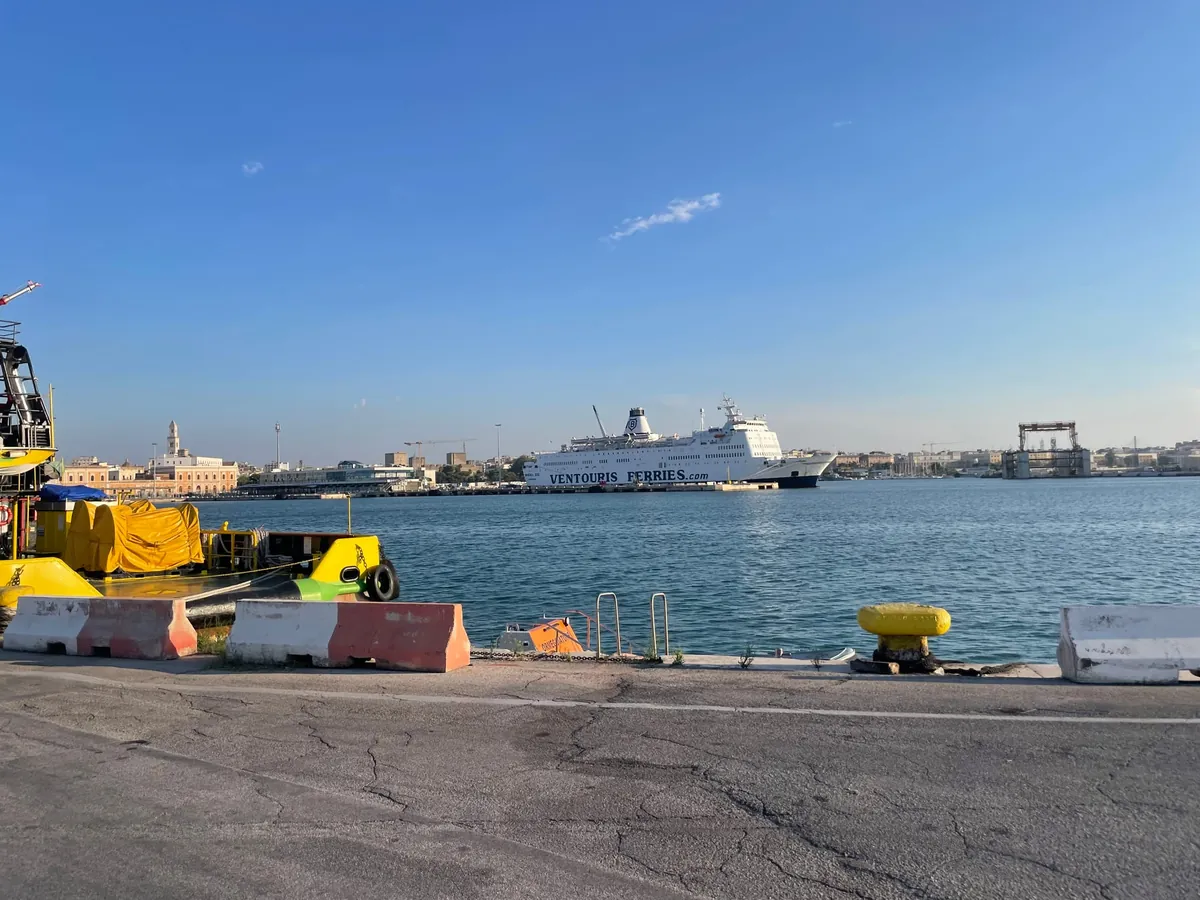 Il traghetto bianco Rigel III di Ventouris Ferries in banchina nel porto di Bari, con la città vecchia sullo sfondo