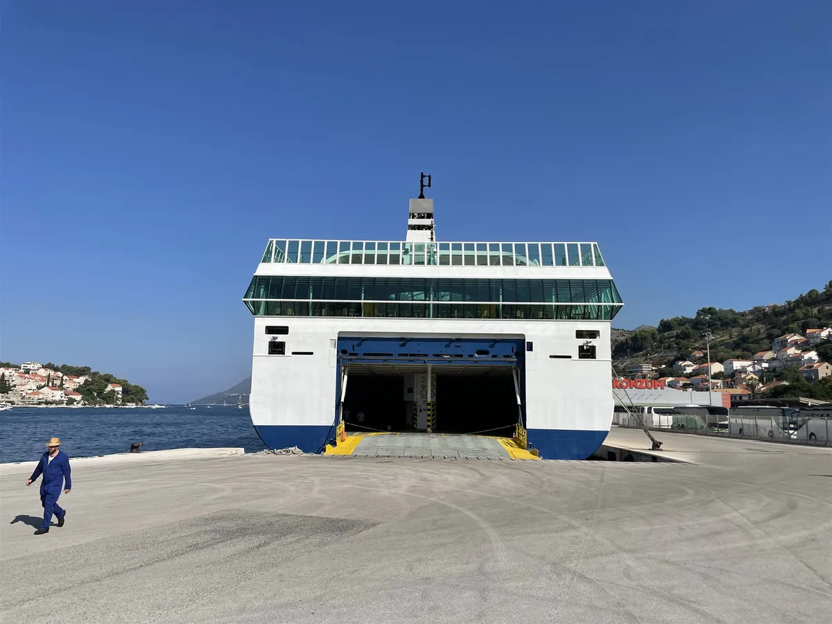 La poppa del traghetto bianco e blu Dalmacija di Jadrolinija in banchina a Dubrovnik, con il portellone aperto e la rampa abbassata sul molo