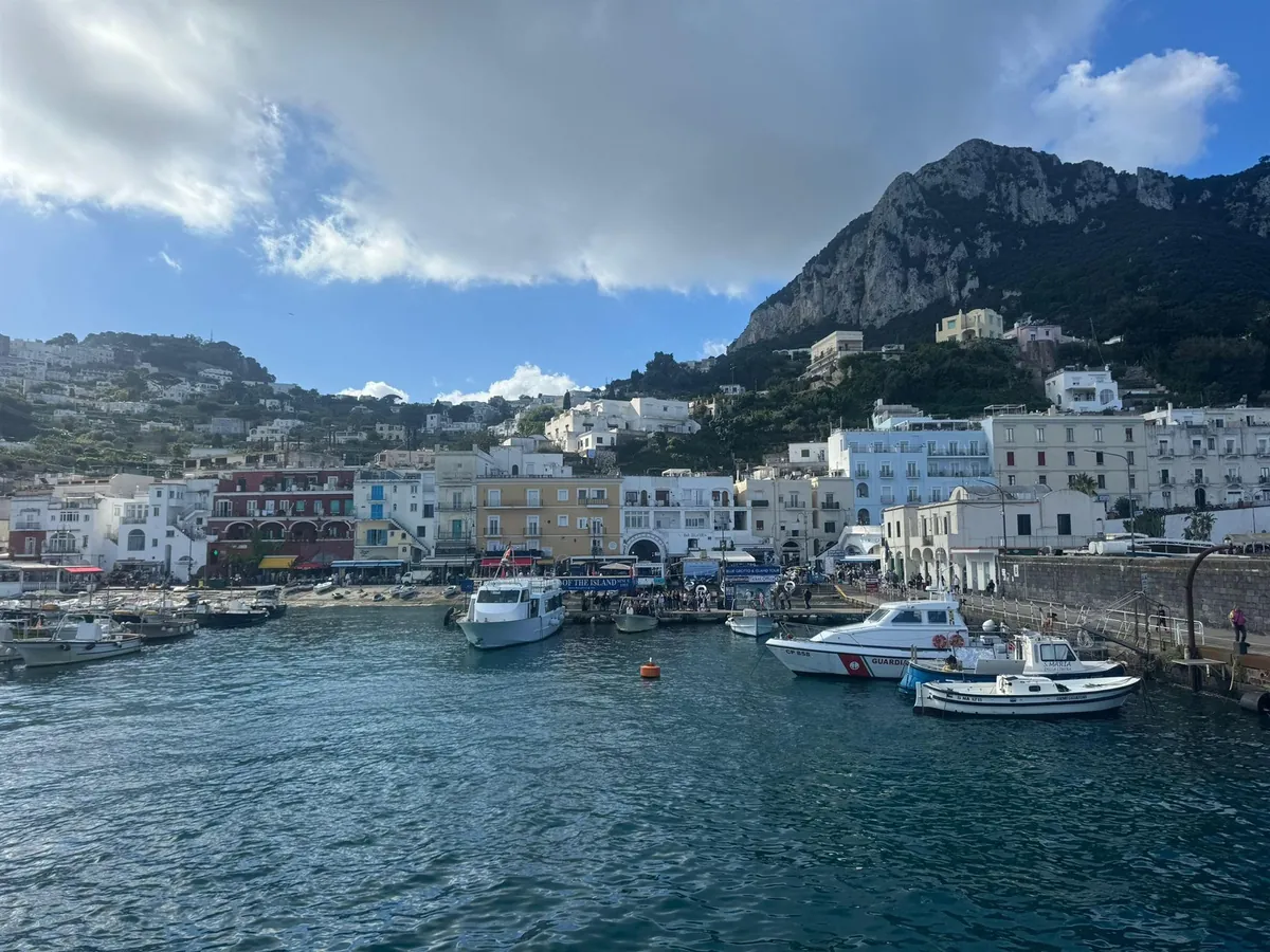 Il porto di Marina Grande a Capri con barche da pesca, case colorate e le rocce sopra